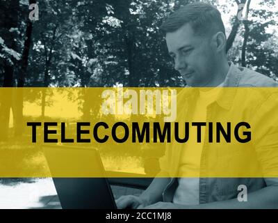 Telecommuting concept. A young man is typing on a laptop in the park. Stock Photo