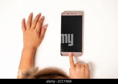 children hands, press the home button on the phone with a broken screen Stock Photo