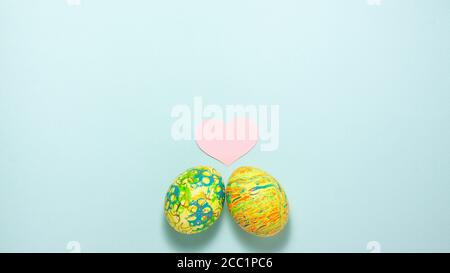 Two easter colorful eggs roll out to each other on blue background. Flat lay with copy space Stock Photo
