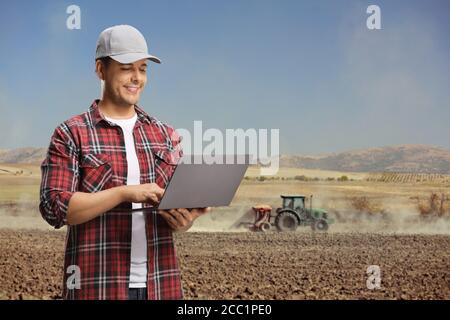 Young agriculture engineer using a laptop computer on a field with a tractor Stock Photo