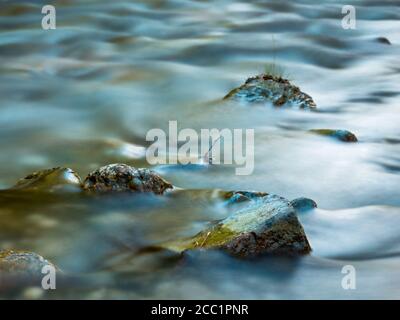 Stream flowing smoothly between rocks in the mountains. Stock Photo