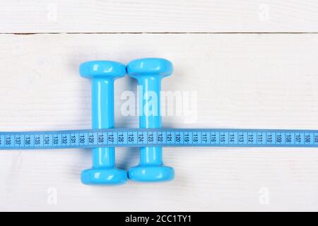 Centimeter tied around sports equipment in cyan blue on wooden vintage  background. Tools for healthy lifestyle. Workout and weight loss concept.  Bottle, apple, measuring tape and jump rope, top view Stock Photo 