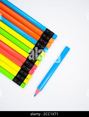 View of a line of different colored wood pencil crayons on white paper background Stock Photo
