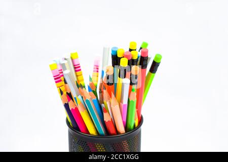 A black colored plastic pencil holder containing many different colored wood pencil crayons Stock Photo