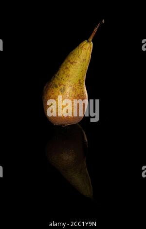 A solitary pear and its reflection against a dark background Stock Photo