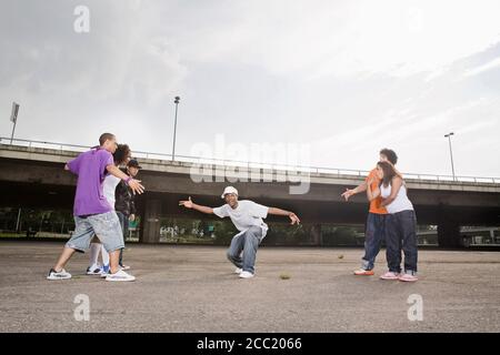 Germany, Cologne, Group of young people breakdancing on street Stock Photo