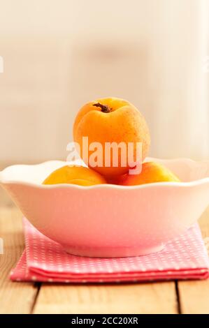 Bowl of apricots on wooden table, close up Stock Photo