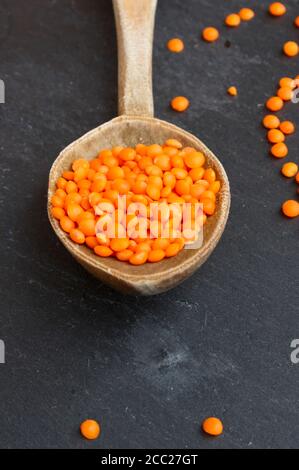 Split red lentils on wooden spoon, close up Stock Photo