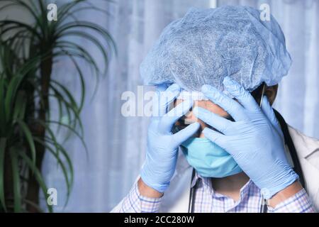 Depressed sad matured doctor covering face with hands  Stock Photo