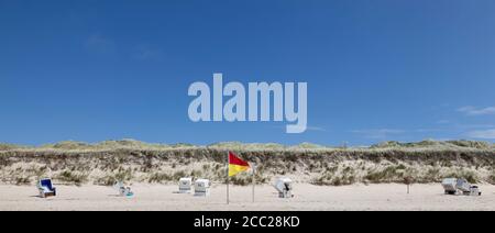 Germany, View of empty beach with roofed wicker beach chairs and flag on Sylt island Stock Photo