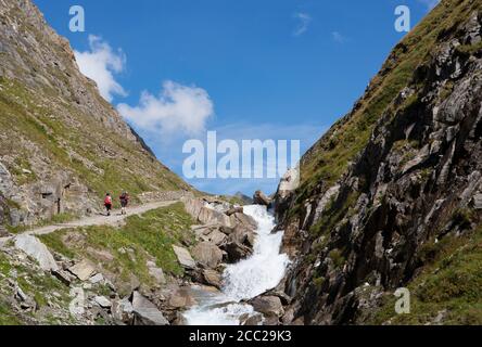Italy, View of Pfunderer Berge with hikers walking near stream