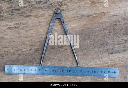 Leather craft tools on a old wood backgrounde. Craftsman work desk . Piece of hide and working handmade tools on a work table. Stock Photo