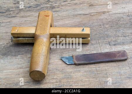 Leather craft tools on a old wood backgrounde. Craftsman work desk . Piece of hide and working handmade tools on a work table. Stock Photo