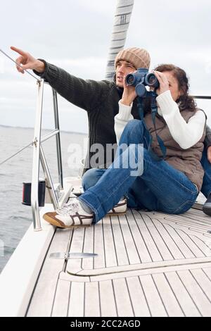 Germany, Baltic Sea, Lübecker Bucht, Young couple on boat, woman looking through binoculars Stock Photo
