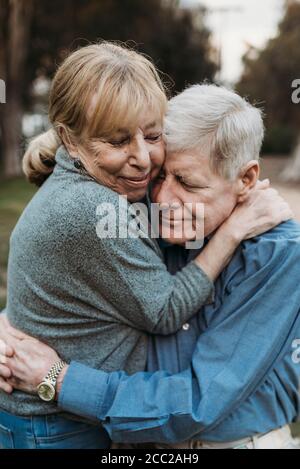 Close up portrait of senior adult couple embracing in forest Stock Photo