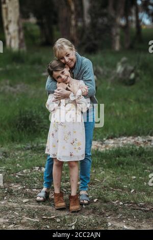 Grandmother and granddaughter embracing and smiling in field Stock Photo