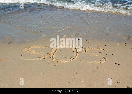 SOS - word drawn on the sand beach with the soft wave. Stock Photo