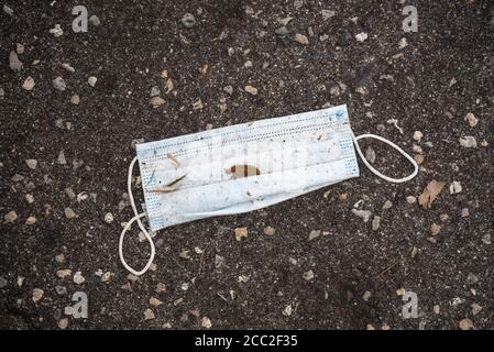 Discarded face mask, used and thrown away in a restaurant parking lot during the Covid-19 Coronavirus Pandemic of 2020. Stock Photo