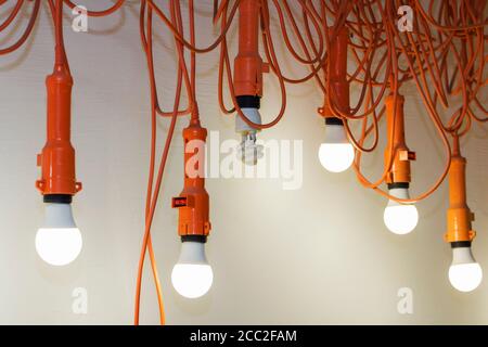 Photo of hanging light bulbs with depth of field. One light does not Shine. Leadership concept.