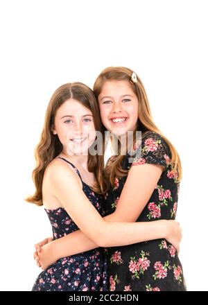 Vertical portrait of two attractive young girls against a white background in a studio or high key. Stock Photo