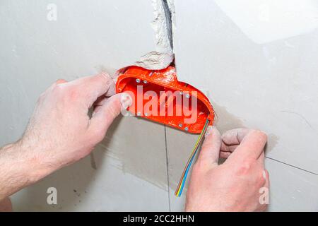 Installation of new sockets. Repair in the apartment. wires outlet and connectors conduit on wall for electrician maintenance installation. Stock Photo