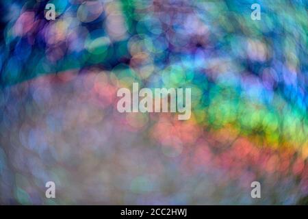 Rainbow sparkle glitter. Abstract backdrop. Colorful glowing rainbow drops and lights on black background. Festive shiny glitter of blurred sequins an Stock Photo