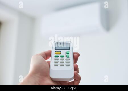 Remote control for air conditioner in hand. Room condition remote control. Air temperature switch for cooling of space. Stock Photo