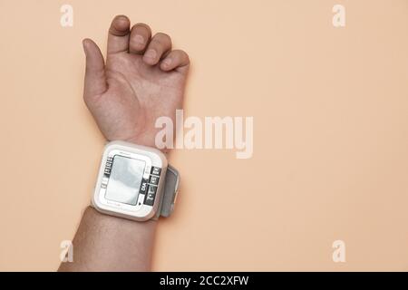 flat lay of man's hand resting on a flat orange background with a tensiometer. health care concept. heart shape Stock Photo