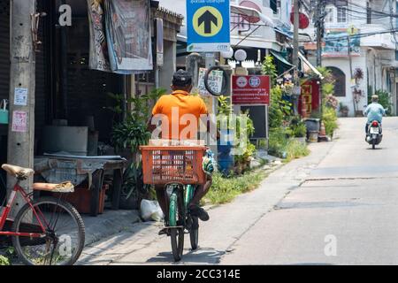 SAMUT PRAKAN, THAILAND, APR 27 2020, A man with basket on bicycle ride on a local road on Sunday at noon Stock Photo