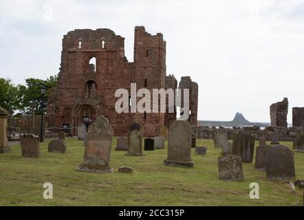 Graveyard of St. Mary's Church and Lindisfarne Priory, with Lindisfarne Castle in background, Holy Island, Northumberland, UK. Stock Photo