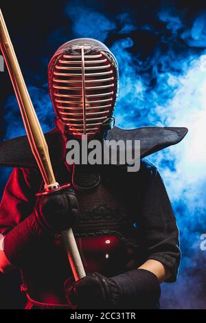 young caucasian kendo fighter in armor practicing with bamboo sword, preparing for competitions. samurai, kendo concept. isolated smoky space Stock Photo