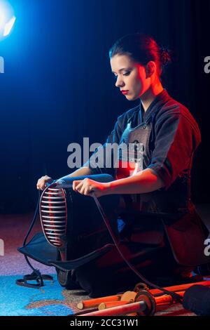 young caucasian female kendo fighter wearing mask, woman in kendo suit keen on traditional martial art Stock Photo