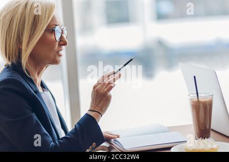 talented psychologist consulting a client in the cafe. close up side view photo. copy space. old smart woman instructing a customer Stock Photo