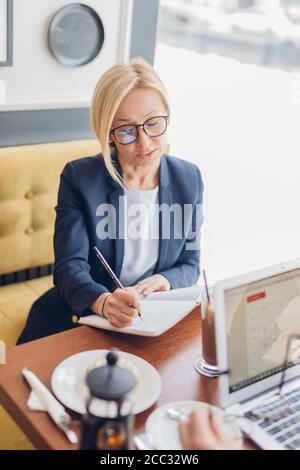 Positive business woman creating the project in the cafe. close up photo. girl concentrated on her work during coffee break Stock Photo