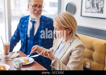 business people tasting yummy cake after meeting. businessman and businesswoman having a break Stock Photo