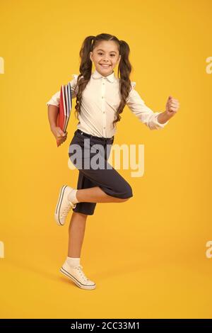 Hurry up. Keep going. Active kid. Girl with books on way to school. Knowledge day. Back to school. Kid cheerful schoolgirl running. Pupil want study. Active child in motion. Beginning school lesson. Stock Photo
