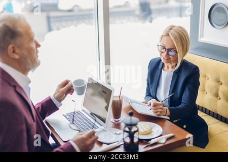 charming blond woman and old man having breakfast and discussing a business plan. close up photo. leisure concept Stock Photo