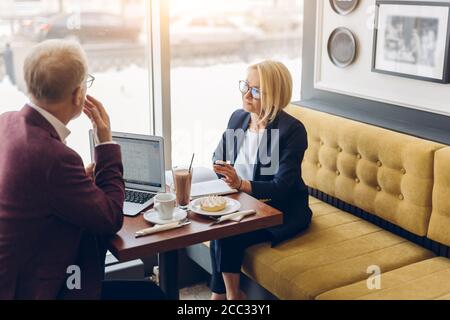 two clever people brainstorming at cafe, developing business strategy using laptop , looking concentrated. Stock Photo
