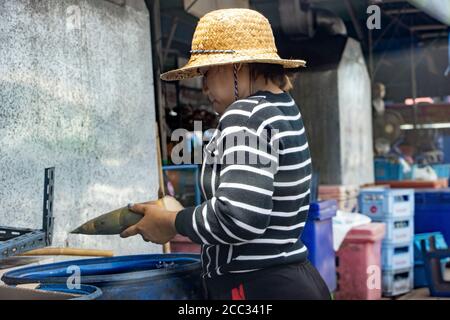 SAMUT PRAKAN, THAILAND, JUN 23 2020, A young woman clean a bamboo shoot at local market. A seller adjust Bamboo shoot vegetable beside the stall at th Stock Photo