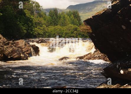 A view of one of the many waterfalls down the River Orchy in Glen Orchy, Scotland showing the rocks, gushing water and surrounding evergreen trees Stock Photo