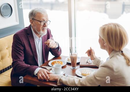Cheerful mature couple having breakfast at cafe while chatting and looking at each other. lifestyle. free time Stock Photo