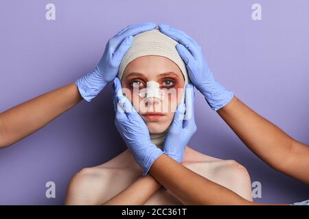 plastic surgeon treating facial injuries. close up portrait, isolated blue background, reconstruction of face after insidents, treating defects Stock Photo