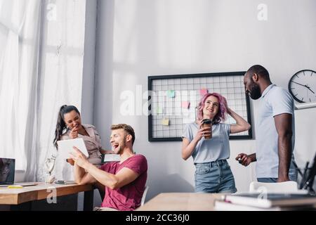 Selective focus of multicultural business people using digital tablet and drinking coffee in office Stock Photo