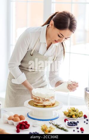 homemade pastry concept. girl concentrated on decorating cake.close up photo. Stock Photo