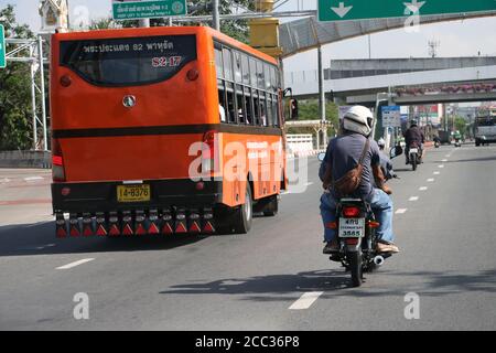 SAMUT PRAKAN, THAILAND, JUN 03 2020, A motorcycle goes around a city bus on the street. Stock Photo