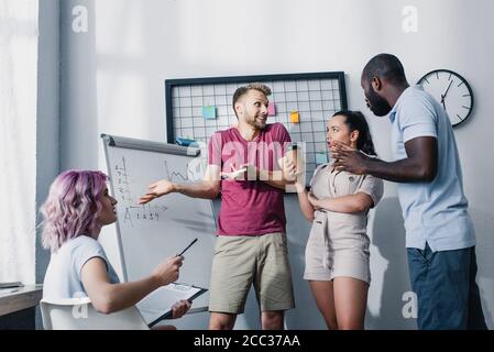 Multicultural business people working near whiteboard in office Stock Photo