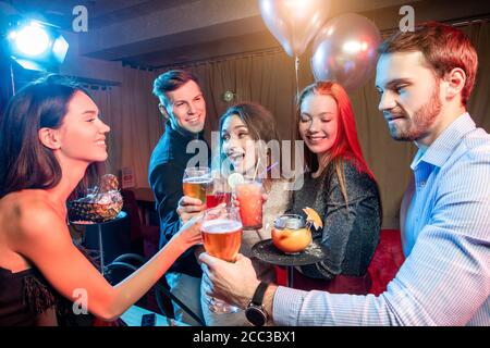 happy group of friends laugh and drink and have fun togeher in karaoke bar, beautiful girls and handsome guys chilling out and rocking together, have Stock Photo