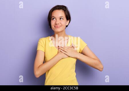 romantic smiling lovely girl expresses her tender feeling, looking up, isolated blue background, studio shot, copy space, girl fells in love, love at Stock Photo
