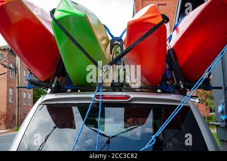Close up, shallow depth of field , bug eye view image of four red and green colored full size kayaks loaded on top of an SUV car using a combination o Stock Photo