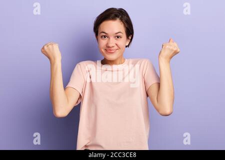 cheerful positive young woman raising her fists with smiling delighted expression , I've done it. student passed exams successfully. feeling and emoti Stock Photo